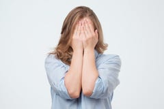 La jeune femme caucasienne couvre le visage de mains, d'isolement sur un fond gris photo libre de droits La jeune femme caucasienne couvre le visage de mains, d'isolement sur un fond gris photo libre de droits