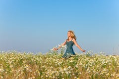La jeune femme heureuse dans des blues-jean qu'un bain de soleil saute dans le domaine des camomiles dans un jour ensoleillé image stock La jeune femme heureuse dans des blues-jean qu'un bain de soleil saute dans le domaine des camomiles dans un jour ensoleillé image stock