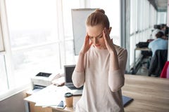 La jeune femme se tient une grande salle de bureau et en gardant ses mains près de la tête Elle a un mal de tête C'est une douleu photo stock La jeune femme se tient une grande salle de bureau et en gardant ses mains près de la tête Elle a un mal de tête C'est une douleu photo stock