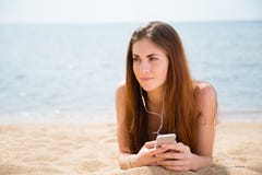 La jeune femme utilise un smartphone sur la plage photographie stock libre de droits La jeune femme utilise un smartphone sur la plage photographie stock libre de droits