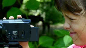 La jeune fille regarde dans la caméra vidéo sur le fond du fond vert de parc banque de vidéos La jeune fille regarde dans la caméra vidéo sur le fond du fond vert de parc banque de vidéos
