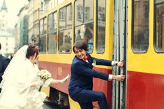 La jeune mariée essaye d'attraper un marié qui s'élève sur un tram Photographie stock La jeune mariée essaye d'attraper un marié qui s'élève sur un tram Photographie stock