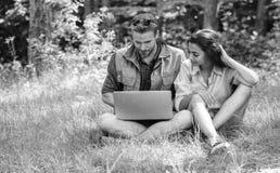 La jeunesse de couples d?pensent des loisirs dehors avec l'ordinateur portable Homme et fille regardant l'?cran d'ordinateur port image libre de droits La jeunesse de couples d?pensent des loisirs dehors avec l'ordinateur portable Homme et fille regardant l'?cran d'ordinateur port image libre de droits