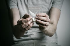 La lucha contra las drogas y tema de la drogadicción: envicie llevar a cabo el paquete de cocaína en una camiseta gris en un fond Fotografía de archivo La lucha contra las drogas y tema de la drogadicción: envicie llevar a cabo el paquete de cocaína en una camiseta gris en un fond Fotografía de archivo