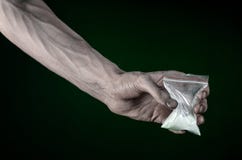 La lucha contra las drogas y tema de la drogadicción: mano sucia que sostiene una cocaína del adicto al bolso en un fondo verde o Fotografía de archivo La lucha contra las drogas y tema de la drogadicción: mano sucia que sostiene una cocaína del adicto al bolso en un fondo verde o Fotografía de archivo