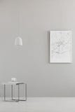 La lumière pendante au-dessus d'une table moderne et une ville tracent l'affiche sur un mur gris dans un intérieur minimaliste de photographie stock libre de droits La lumière pendante au-dessus d'une table moderne et une ville tracent l'affiche sur un mur gris dans un intérieur minimaliste de photographie stock libre de droits
