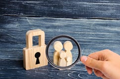 La lupa está mirando a la familia joven con los niños se está colocando cerca de un candado de madera concepto de una familia fue imagen de archivo La lupa está mirando a la familia joven con los niños se está colocando cerca de un candado de madera concepto de una familia fue imagen de archivo