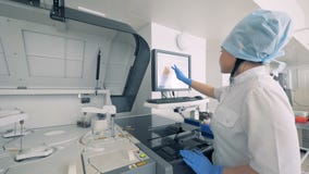 La macchina analizzante biochimica sta dirigenda da un tecnico di laboratorio ad un'installazione produttiva farmaceutica video d archivio La macchina analizzante biochimica sta dirigenda da un tecnico di laboratorio ad un'installazione produttiva farmaceutica video d archivio