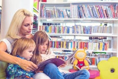 La madre con la bambina ed il ragazzo ha letto insieme il libro in salotto immagini stock libere da diritti La madre con la bambina ed il ragazzo ha letto insieme il libro in salotto immagini stock libere da diritti