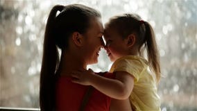 La madre e sua figlia stanno stringendo a sé La pioggia è su fondo Stanno avendo molto divertimento Poiché l'oggi è il giorno del video d archivio La madre e sua figlia stanno stringendo a sé La pioggia è su fondo Stanno avendo molto divertimento Poiché l'oggi è il giorno del video d archivio