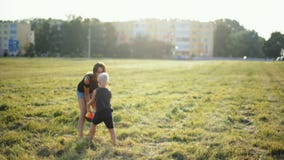 La madre está jugando la bola con el pequeño niño en hierba en Niza la puesta del sol metrajes La madre está jugando la bola con el pequeño niño en hierba en Niza la puesta del sol metrajes