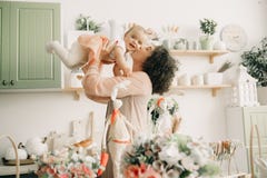 La madre felice gioca e bacia il suo bambino nella cucina fotografia stock libera da diritti La madre felice gioca e bacia il suo bambino nella cucina fotografia stock libera da diritti