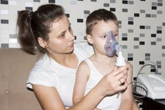 La madre hace la inhalación a su hijo en casa Prevención de la tos El niño respira en el inhalador fotos de archivo libres de regalías La madre hace la inhalación a su hijo en casa Prevención de la tos El niño respira en el inhalador fotos de archivo libres de regalías