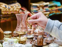 La main femelle tient un verre turc de thé de souvenir avec une cuillère image stock La main femelle tient un verre turc de thé de souvenir avec une cuillère image stock