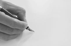 La main tenant le stylo-plume écrivent sur le livre blanc image stock La main tenant le stylo-plume écrivent sur le livre blanc image stock
