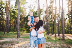 La mam?, el pap? y la hija de la familia se sienta en el pap? en los hombros, y los padres se besan en la naturaleza en el bosque fotografía de archivo libre de regalías La mam?, el pap? y la hija de la familia se sienta en el pap? en los hombros, y los padres se besan en la naturaleza en el bosque fotografía de archivo libre de regalías
