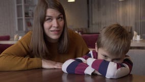 La maman calme le petit fils qui a été offensé par sa séance à une table dans un café banque de vidéos La maman calme le petit fils qui a été offensé par sa séance à une table dans un café banque de vidéos