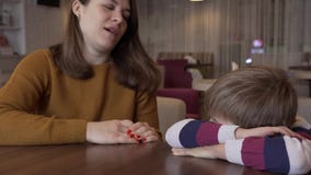 La maman calme le petit fils qui a été offensé par sa séance à une table dans un café banque de vidéos La maman calme le petit fils qui a été offensé par sa séance à une table dans un café banque de vidéos