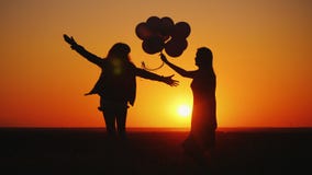 La maman et la fille ont l'amusement au coucher du soleil, dansent et tiennent des ballons images libres de droits La maman et la fille ont l'amusement au coucher du soleil, dansent et tiennent des ballons images libres de droits
