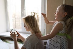 La mamma e la figlia stanno sedendo dalla finestra fotografia stock libera da diritti La mamma e la figlia stanno sedendo dalla finestra fotografia stock libera da diritti