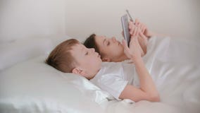 La mamma ed il figlio svegliano e Internet di lettura rapida in loro telefoni cellulari Vista laterale archivi video La mamma ed il figlio svegliano e Internet di lettura rapida in loro telefoni cellulari Vista laterale archivi video