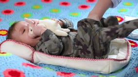 La mamma rimuove i vestiti da un bambino Il bambino sta giocando con un giocattolo molle mentre si trovava su un letto I vestiti La mamma rimuove i vestiti da un bambino Il bambino sta giocando con un giocattolo molle mentre si trovava su un letto I vestiti