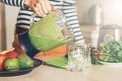 La mano de la mujer que vierte el smoothie verde en un vidrio fotos de archivo La mano de la mujer que vierte el smoothie verde en un vidrio fotos de archivo