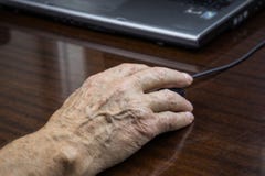 La mano de un hombre mayor utiliza un ratón del ordenador imágenes de archivo libres de regalías La mano de un hombre mayor utiliza un ratón del ordenador imágenes de archivo libres de regalías