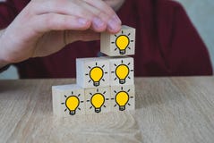 La mano escogió los cubos de madera con el símbolo del bulbo de la luz ámbar en la tabla de madera Nuevos idea, conceptos de la i imágenes de archivo libres de regalías La mano escogió los cubos de madera con el símbolo del bulbo de la luz ámbar en la tabla de madera Nuevos idea, conceptos de la i imágenes de archivo libres de regalías