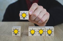 La mano escogió los cubos de madera con el símbolo del bulbo de la luz ámbar en la tabla de madera Nuevos idea, conceptos de la i foto de archivo La mano escogió los cubos de madera con el símbolo del bulbo de la luz ámbar en la tabla de madera Nuevos idea, conceptos de la i foto de archivo