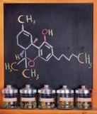 La marijuana médica clasificada sacude contra tablero con fórmula de THC imágenes de archivo libres de regalías La marijuana médica clasificada sacude contra tablero con fórmula de THC imágenes de archivo libres de regalías