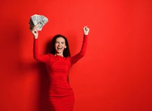 La morenita fresca joven en un vestido rojo disfruta en una gran cantidad de dinero en sus manos que ella gana foto de archivo libre de regalías La morenita fresca joven en un vestido rojo disfruta en una gran cantidad de dinero en sus manos que ella gana foto de archivo libre de regalías
