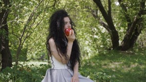 La morenita hermosa se sienta en jardín del verano y come la manzana roja metrajes La morenita hermosa se sienta en jardín del verano y come la manzana roja metrajes