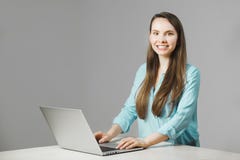 La muchacha agradable se sienta en el ordenador portátil moderno y sonríe imagen de archivo libre de regalías La muchacha agradable se sienta en el ordenador portátil moderno y sonríe imagen de archivo libre de regalías