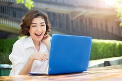 La muchacha asiática feliz que ríe y que señala en la pantalla del ordenador portátil encendido aventaja foto de archivo libre de regalías La muchacha asiática feliz que ríe y que señala en la pantalla del ordenador portátil encendido aventaja foto de archivo libre de regalías