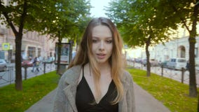 La muchacha atractiva va a lo largo de un callejón de la ciudad en un vestido negro elegante en el slo-MES metrajes La muchacha atractiva va a lo largo de un callejón de la ciudad en un vestido negro elegante en el slo-MES metrajes