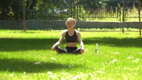 La muchacha bonita está haciendo yoga en parque almacen de metraje de vídeo La muchacha bonita está haciendo yoga en parque almacen de metraje de vídeo