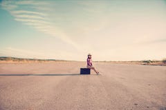 La muchacha del inconformista se sienta en la maleta fotografía de archivo La muchacha del inconformista se sienta en la maleta fotografía de archivo