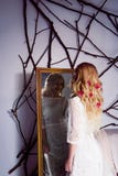 La muchacha hermosa en un vestido blanco largo que mira en el espejo fotografía de archivo La muchacha hermosa en un vestido blanco largo que mira en el espejo fotografía de archivo