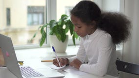 La muchacha hermosa joven se está sentando en la tabla y está haciendo la preparación usando el nuevo ordenador portátil moderno almacen de metraje de vídeo La muchacha hermosa joven se está sentando en la tabla y está haciendo la preparación usando el nuevo ordenador portátil moderno almacen de metraje de vídeo