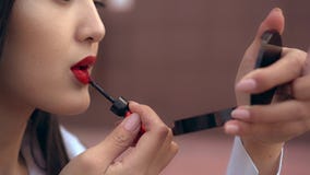 La muchacha japonesa hermosa pinta sus labios con la barra de labios roja Luce increíble de la persona almacen de video La muchacha japonesa hermosa pinta sus labios con la barra de labios roja Luce increíble de la persona almacen de video