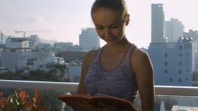 La muchacha linda vuelca las páginas del diario en terraza del tejado La muchacha linda vuelca las páginas del diario en terraza del tejado
