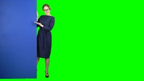 La muchacha mira a escondidas hacia fuera y señala en la cartelera Pantalla verde almacen de metraje de vídeo La muchacha mira a escondidas hacia fuera y señala en la cartelera Pantalla verde almacen de metraje de vídeo