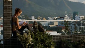 La muchacha rubia se sienta en terraza del tejado escribe en diario La muchacha rubia se sienta en terraza del tejado escribe en diario