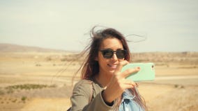 La muchacha sonriente atractiva joven de la raza mixta toma la foto panorámica del desierto en un teléfono móvil Mujer turística almacen de metraje de vídeo La muchacha sonriente atractiva joven de la raza mixta toma la foto panorámica del desierto en un teléfono móvil Mujer turística almacen de metraje de vídeo