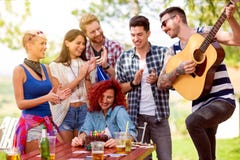 La muchacha tímida del cumpleaños con los amigos que aplauden y juega la canción del cumpleaños en la guitarra fotografía de archivo libre de regalías La muchacha tímida del cumpleaños con los amigos que aplauden y juega la canción del cumpleaños en la guitarra fotografía de archivo libre de regalías
