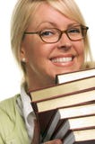 La mujer atractiva sonriente lleva la pila de libros fotografía de archivo La mujer atractiva sonriente lleva la pila de libros fotografía de archivo