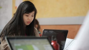 La mujer bastante china trabaja en de computadora personal en estudio La mujer bastante china trabaja en de computadora personal en estudio