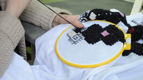 La mujer borda a mano el bordado ucraniano en la tela blanca con los hilos de la lana negra en la opinión correcta del aro metrajes La mujer borda a mano el bordado ucraniano en la tela blanca con los hilos de la lana negra en la opinión correcta del aro metrajes
