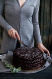 La mujer corta cierre de la torta de chocolate Tonos oscuros foto de archivo libre de regalías La mujer corta cierre de la torta de chocolate Tonos oscuros foto de archivo libre de regalías